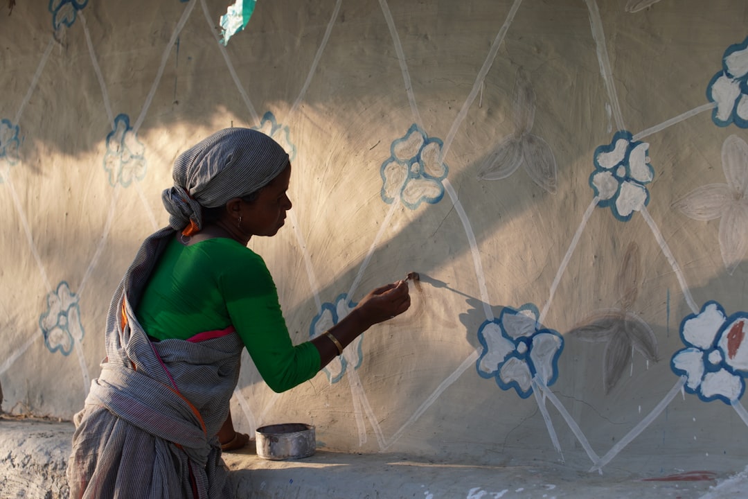 Woman painting flowers on a textured wall